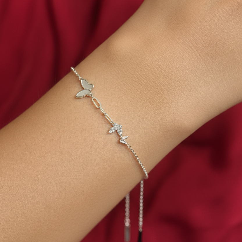 Silver bracelet with butterfly charms in a black box on a red fabric background