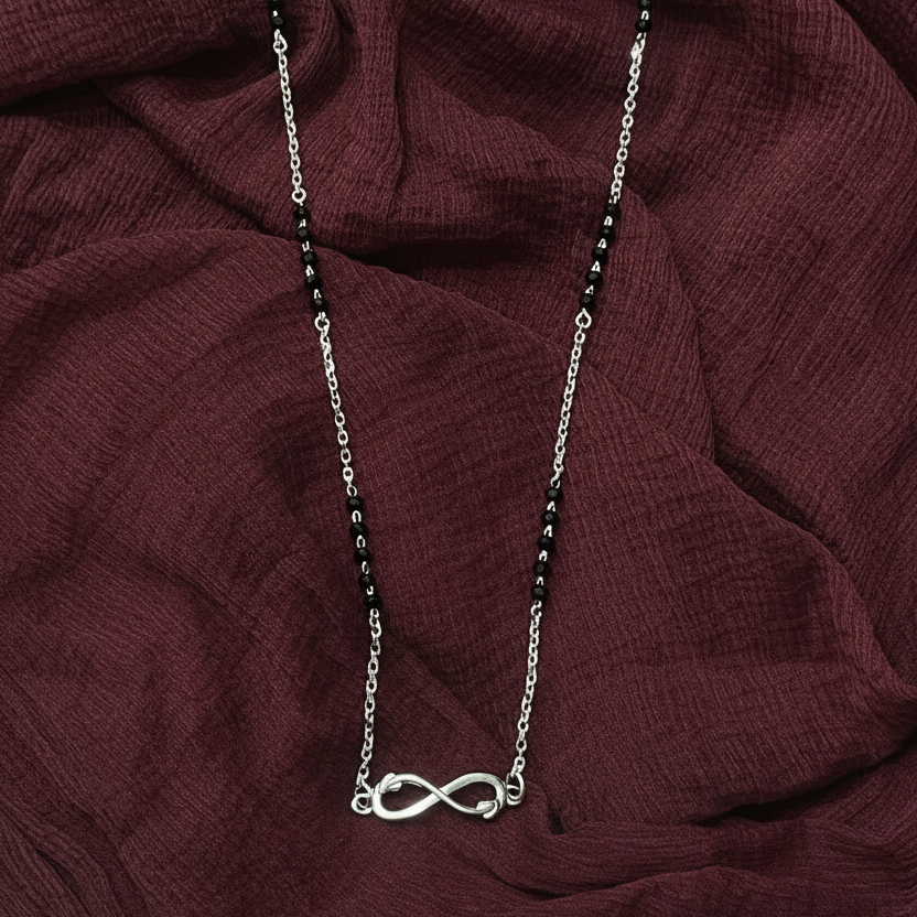 Necklace with an infinity symbol pendant on a red fabric background