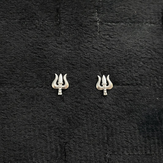 Two silver earrings on a blue fabric background