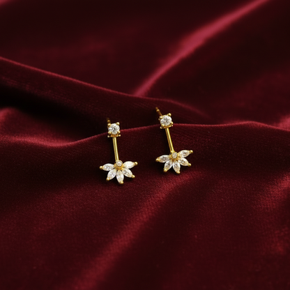 Gold earrings with diamond-like stones on a red velvet background