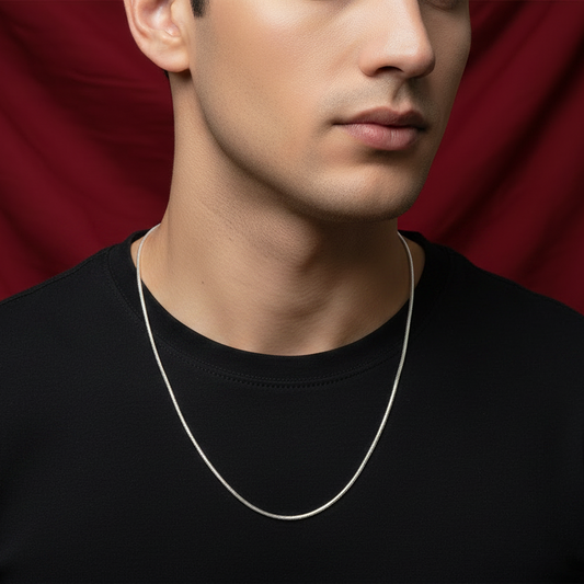 Man wearing a silver necklace against a red curtain background