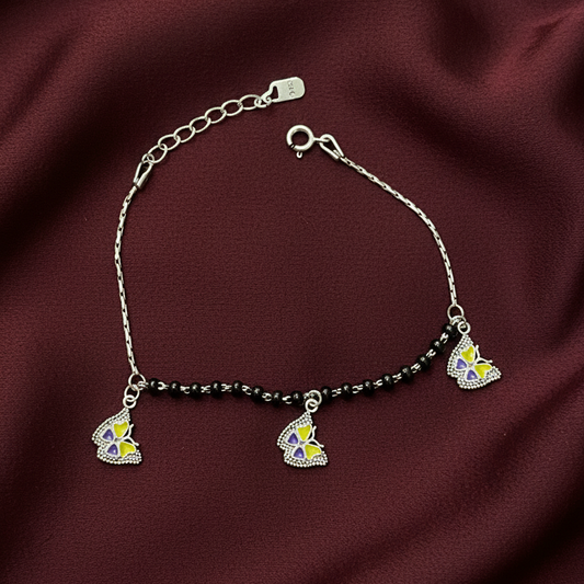 Silver bracelet with colorful charms on a red fabric background