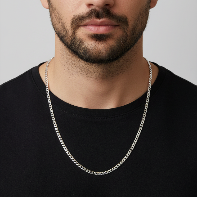 Man wearing a silver chain necklace against a plain background
