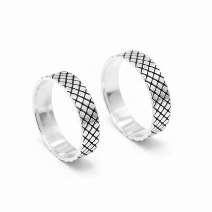 Pair of silver hoop earrings with black grid pattern on a white background