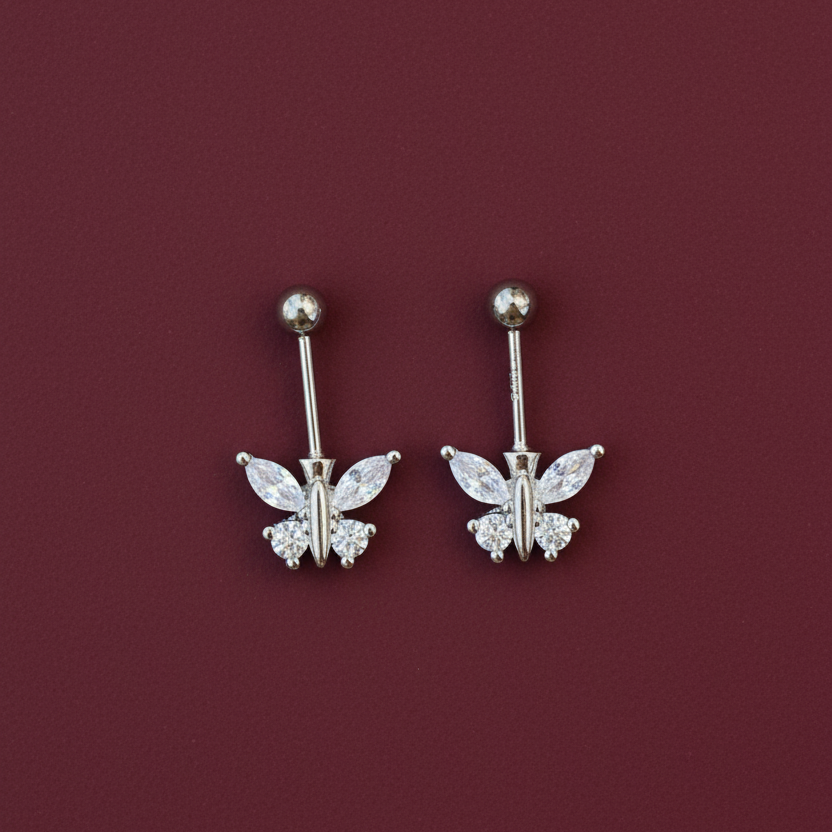 Pair of silver butterfly earrings on a burgundy background