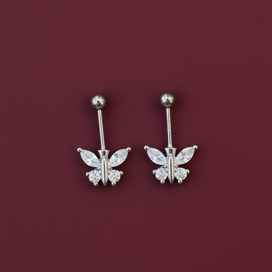 Pair of silver butterfly earrings on a burgundy background