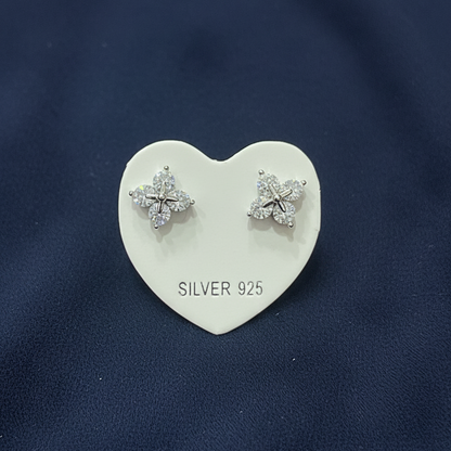 Silver earrings on a heart-shaped stand against a red textured background