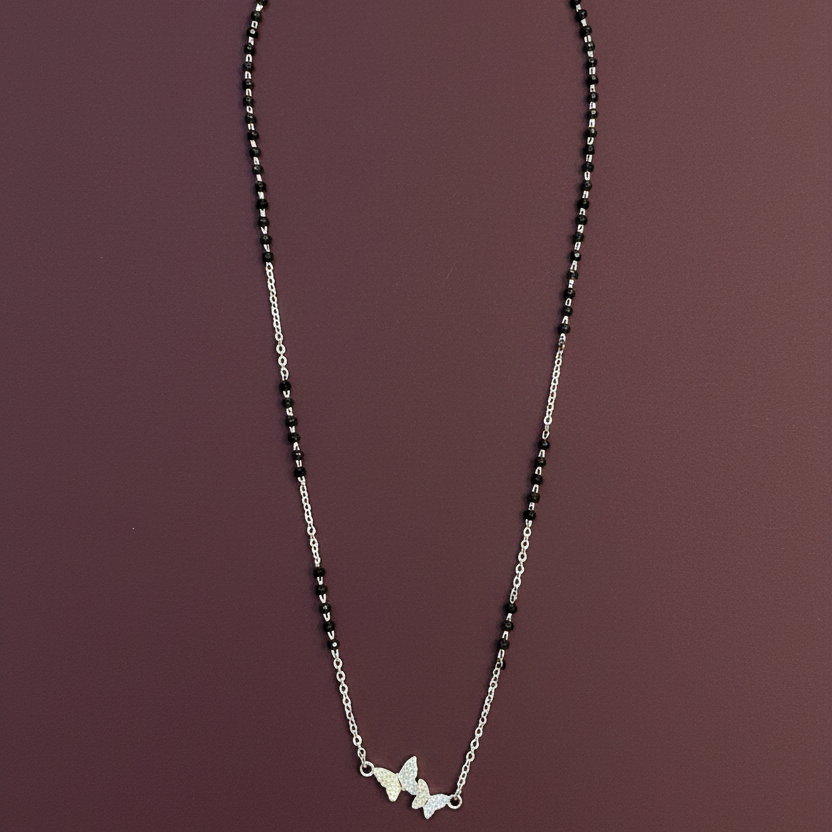Silver necklace with butterfly pendants on a red fabric background