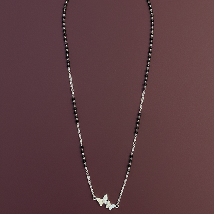 Silver necklace with butterfly pendants on a red fabric background