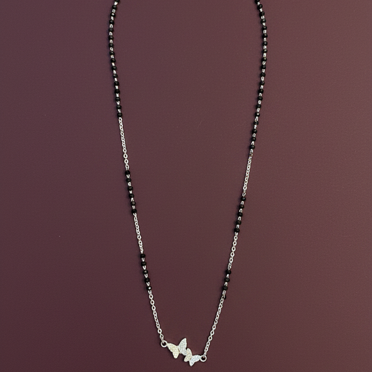 Silver necklace with butterfly pendants on a red fabric background