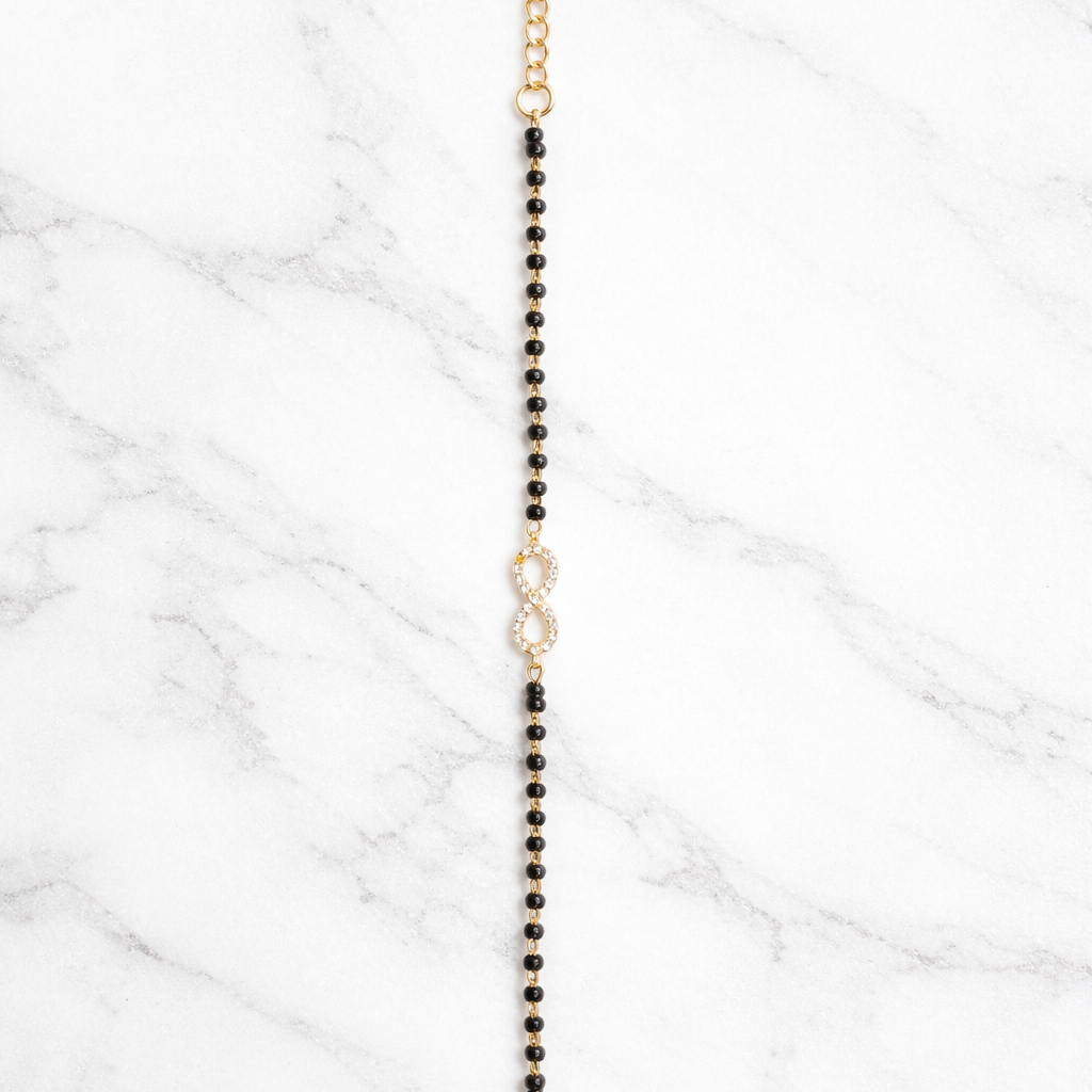 Black beaded necklace with gold clasp on a marble surface