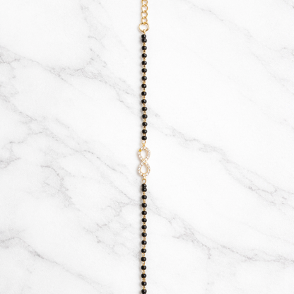 Black beaded necklace with gold clasp on a marble surface