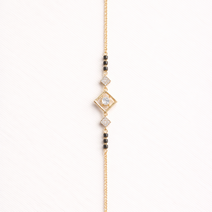 Gold bracelet with diamond-shaped clasp and beads on a white background