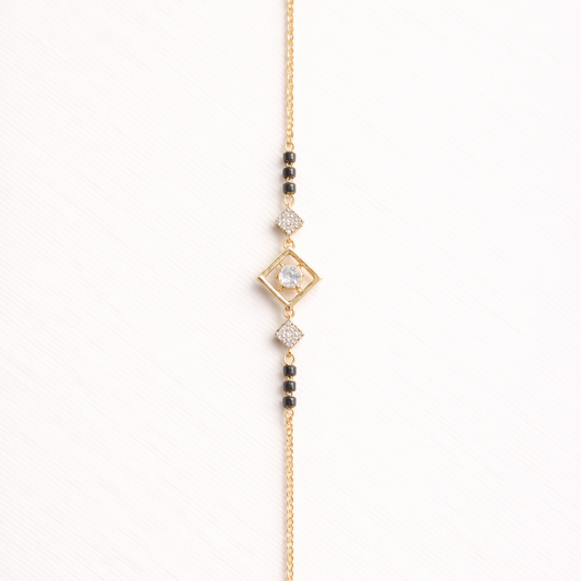 Gold bracelet with diamond-shaped clasp and beads on a white background