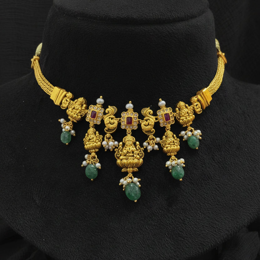 Gold necklace with green gemstones on a red cushion