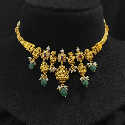 Gold necklace with green gemstones on a red cushion