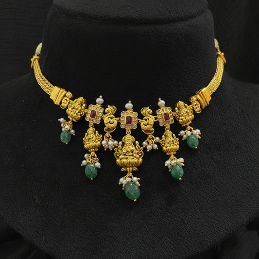 Gold necklace with green gemstones on a red cushion