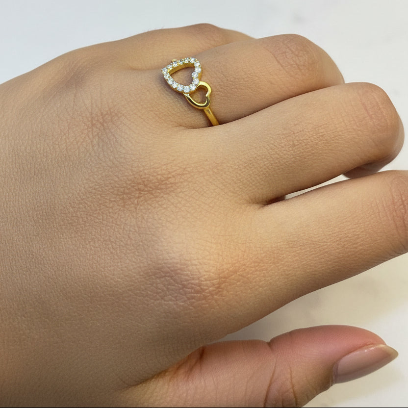 Gold ring with a heart-shaped diamond on a hand against a red fabric background