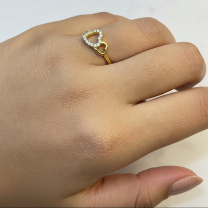 Gold ring with a heart-shaped diamond on a hand against a red fabric background