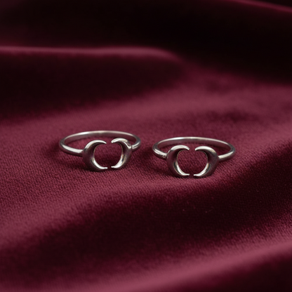 Two silver crescent moon open Toe rings displayed on a deep burgundy velvet fabric background.