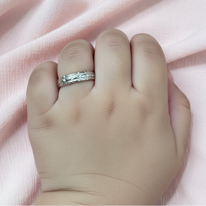 Silver ring on a finger with a pink fabric background