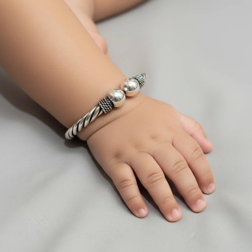 Child's hand wearing a silver bracelet on a light gray background