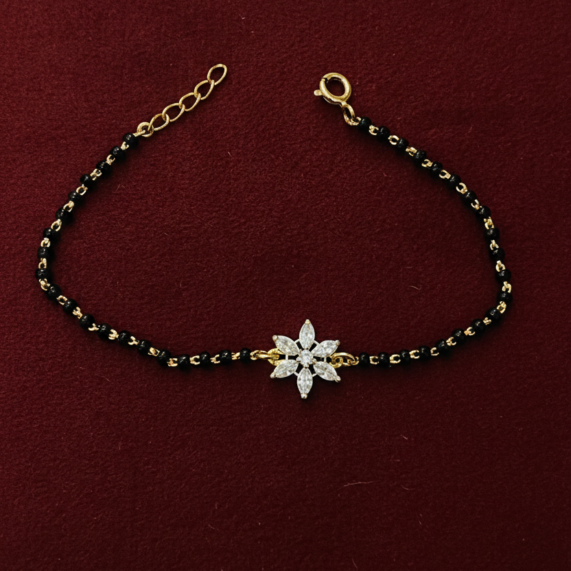 Bracelet with black and gold beads and a silver flower charm on a red background