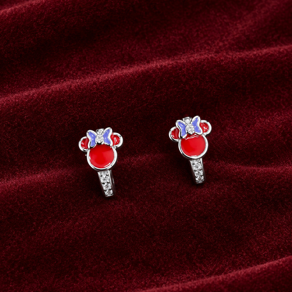 A pair of silver stud earrings with red, white, and blue enamel Mickey Mouse head designs, displayed on a dark green textured fabric background.
