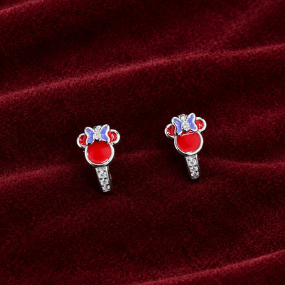 A pair of silver stud earrings with red, white, and blue enamel Mickey Mouse head designs, displayed on a dark green textured fabric background.