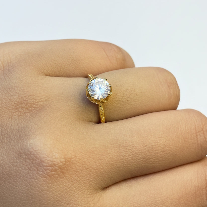 Gold ring with a diamond on a person's finger against a red fabric background