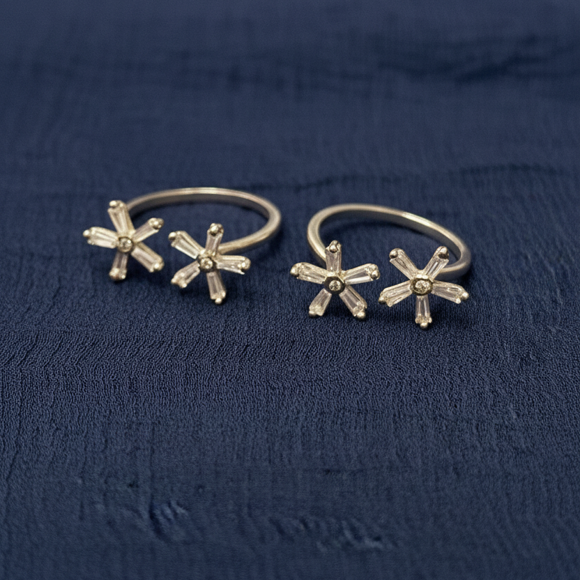 Gold floral hoop earrings on a red textured fabric background