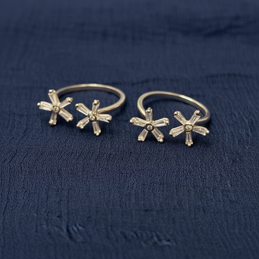 Gold floral hoop earrings on a red textured fabric background
