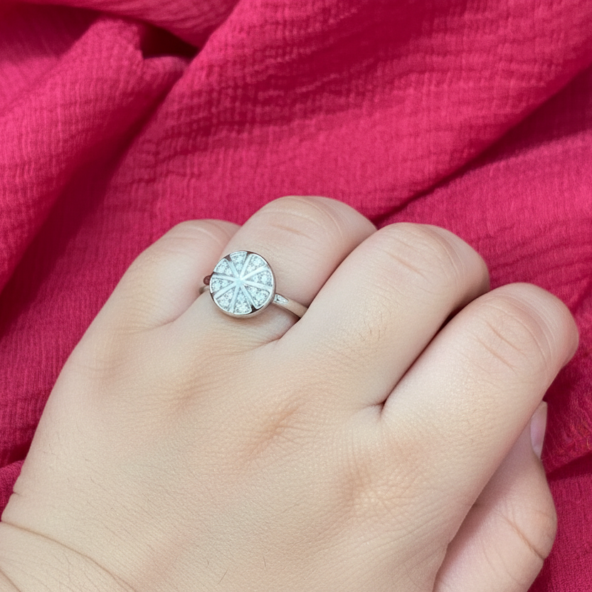 Hand wearing a diamond ring against a pink fabric background