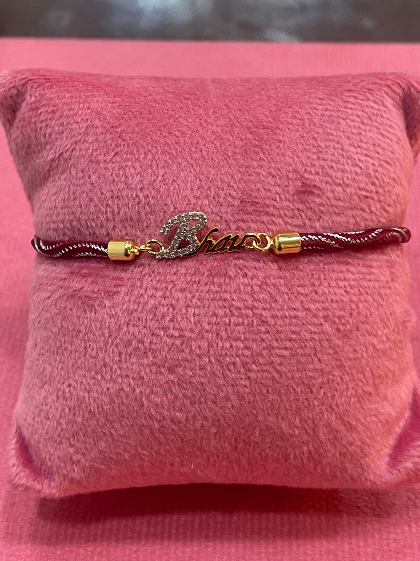Gold-Plated Bhaiya Name Rakhi for Brother | CZ Script Charm on Maroon & Gold Twisted Thread
