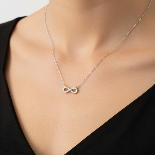 Silver necklace with an infinity symbol pendant on a black card against a red fabric background