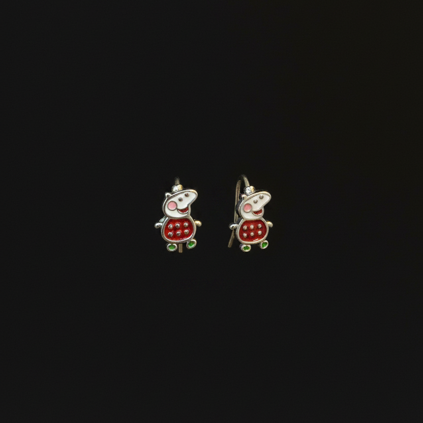 Two small turtle-shaped earrings on a person's finger against a red fabric background