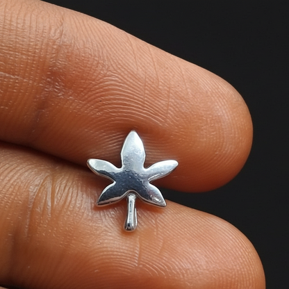 Silver star-shaped earring on a finger against a red fabric background