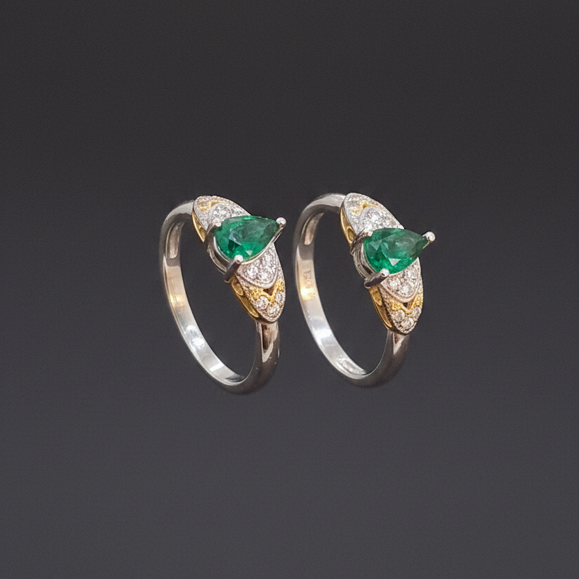 Three emerald and diamond rings on a finger against a pink background