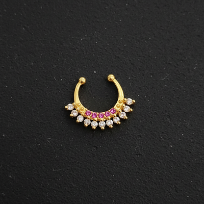 Gold nose ring with gemstones on a teal fabric background