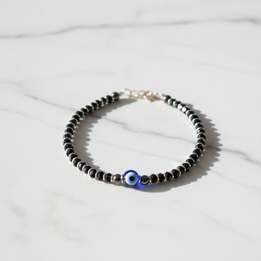 Beaded bracelet with a blue eye charm on a pink surface