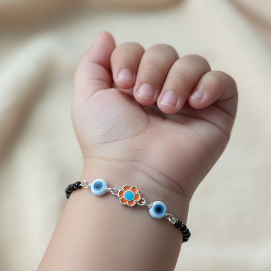 Child's wrist wearing a bracelet with eye-shaped charms on a neutral background