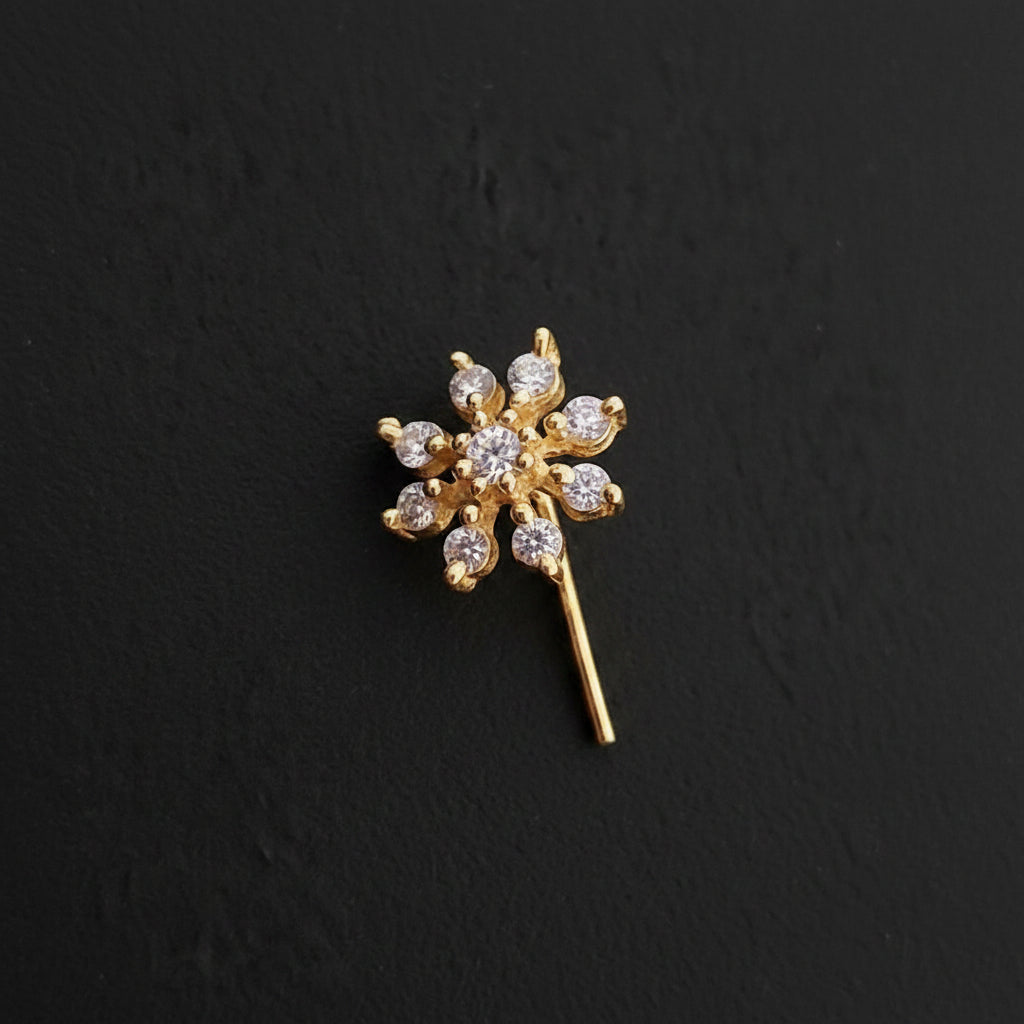 Gold flower-shaped earring on a blue textured background