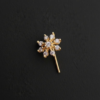 Gold flower-shaped earring on a blue textured background