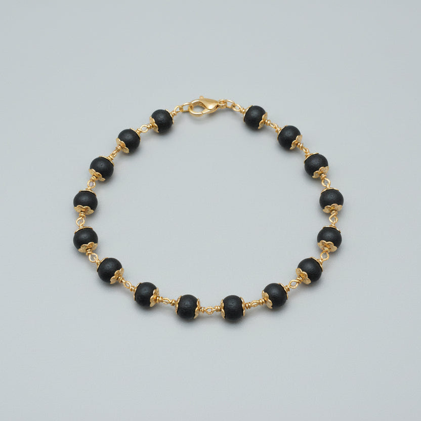 karungali Black beaded bracelet necklace with gold accents on a red fabric background