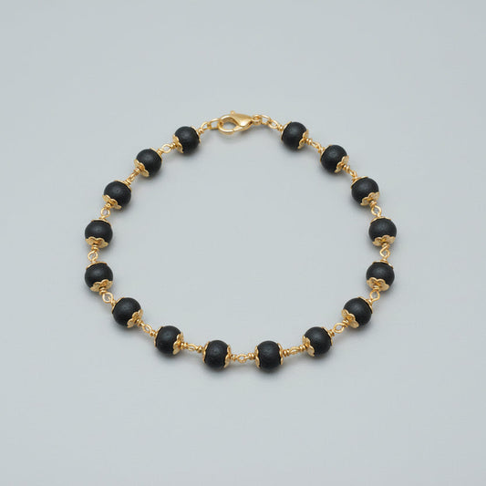 karungali Black beaded bracelet necklace with gold accents on a red fabric background