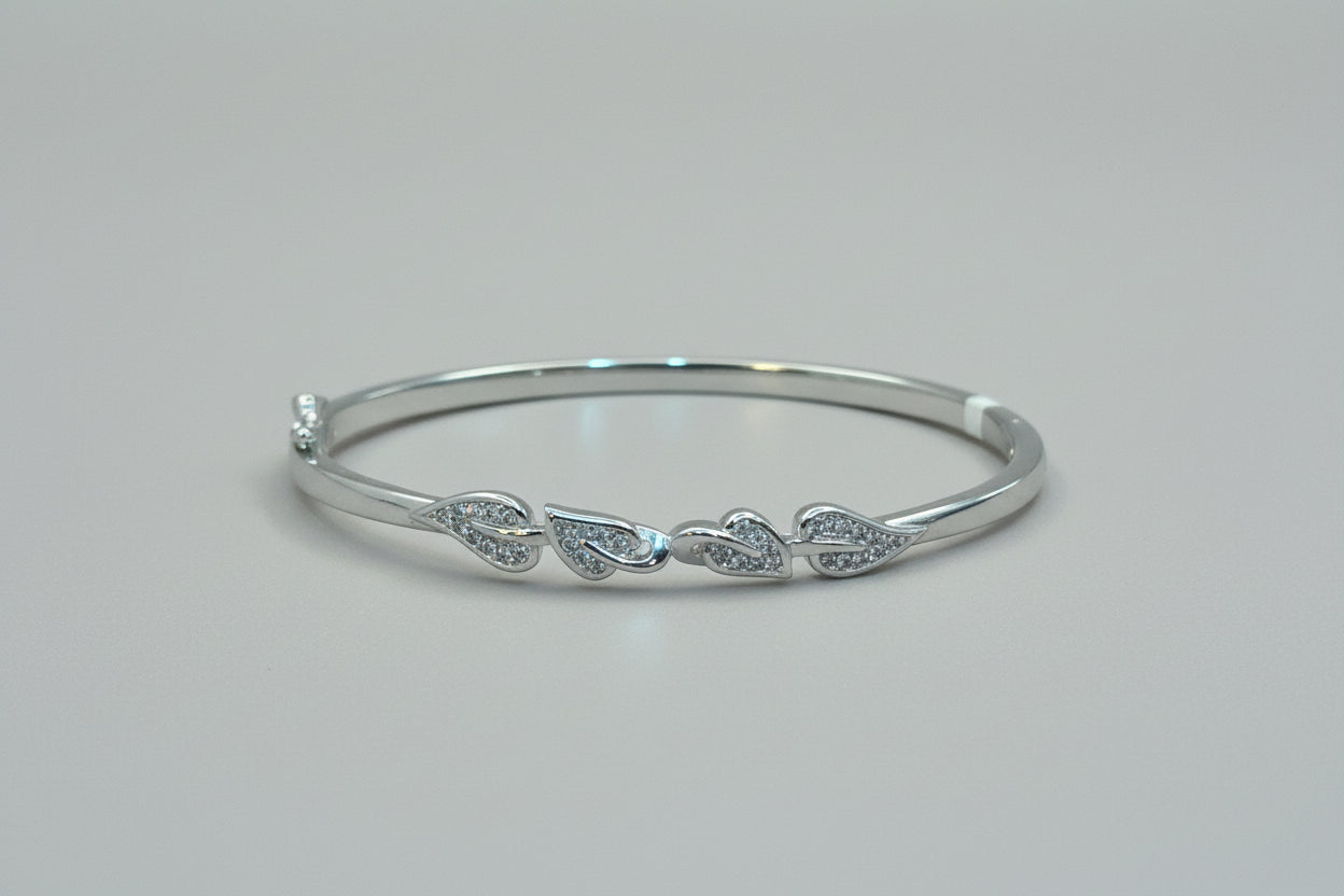 Silver bracelet with leaf designs on a hand against a red fabric background