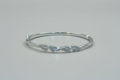 Silver bracelet with leaf designs on a hand against a red fabric background