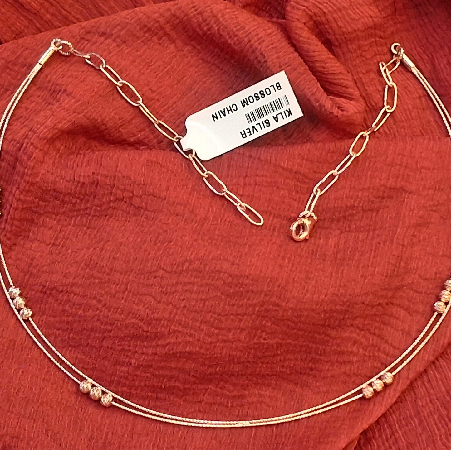 Gold necklace with a tag on a red fabric background