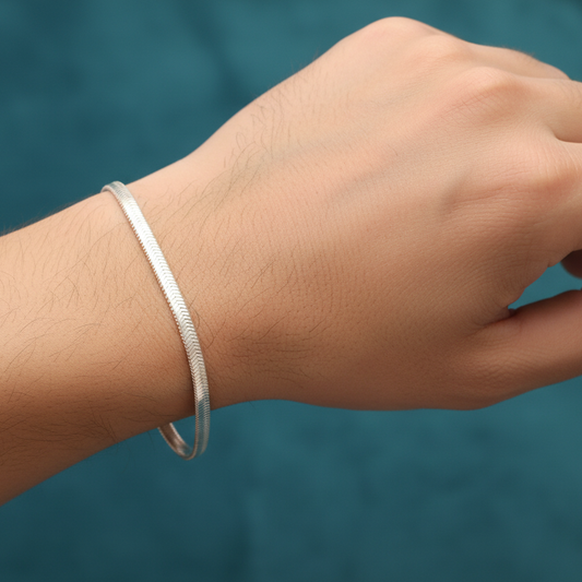Silver bracelet on a wrist against a blue background
