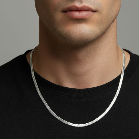 Man wearing a silver necklace against a gray background